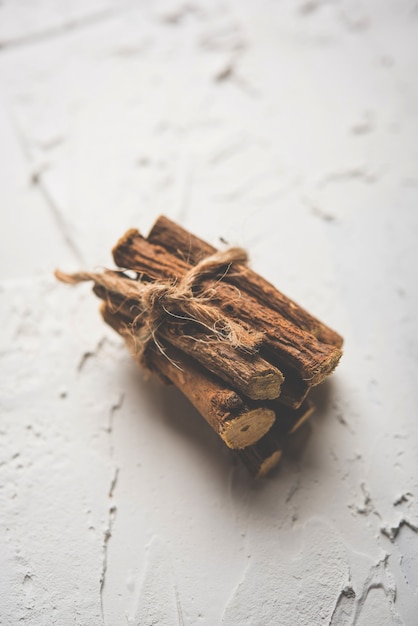 Photo ayurvedic mulethi or liquorice root stick or jeshthamadh powder served in a bowl over moody background