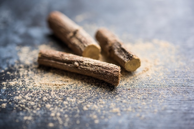 Photo ayurvedic mulethi or liquorice root stick or jeshthamadh powder served in a bowl over moody background