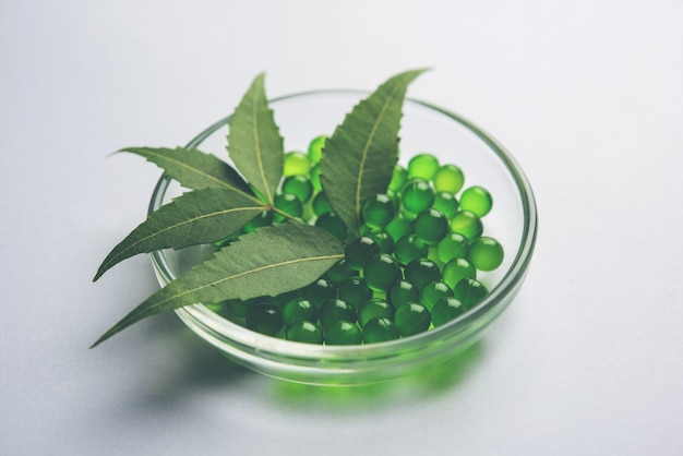 ayurvedic neem pills is an ancient indian medicine used for treating skin deceases and diabetes. served over white background with fresh leaves
