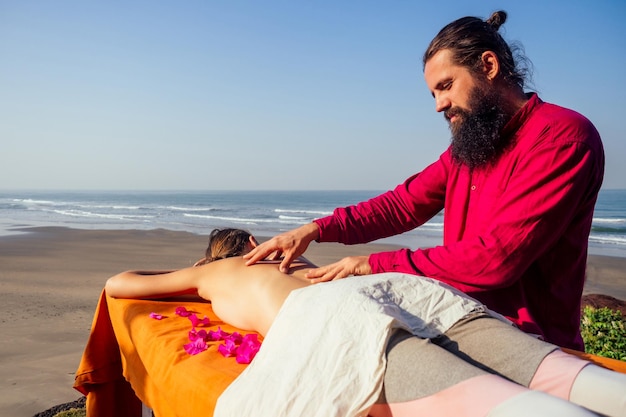 Ayurvedic relaxing massage ,health woman in spa salon getting massage the holiday beach.Beautiful girl enjoying day spa resort, lying down on the table treatment procedure.male master neck therapist