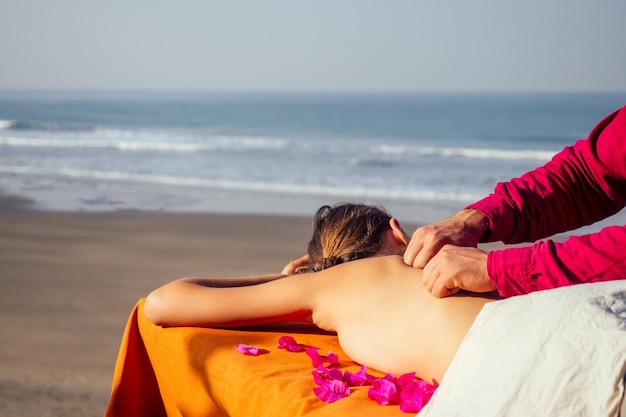 Ayurvedic relaxing massage health woman in spa salon getting massage the holiday beachBeautiful girl enjoying day spa resort lying down on the table treatment proceduremale master neck therapist