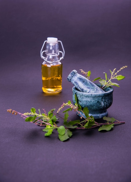 사진 ayurvedic tulsi 오일, 유리병에 허브 추출물의 여왕, 신선한 녹색 바질 가지와 페슬이 있는 모르타르. 화려한 배경 위에 절연. 선택적 초점