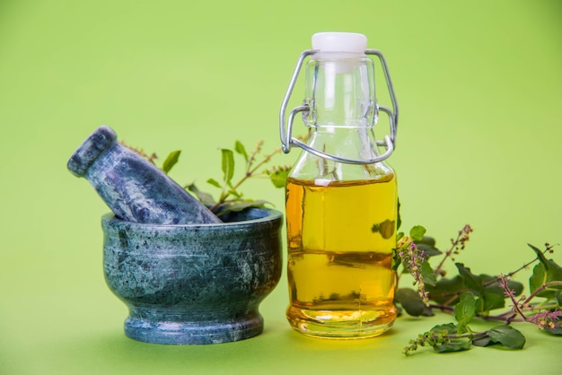 Ayurvedic Tulsi 오일, 유리병에 허브 추출물의 여왕, 신선한 녹색 바질 가지와 페슬이 있는 모르타르. 화려한 배경 위에 절연. 선택적 초점