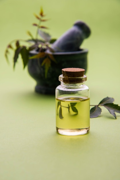 Ayurvedische antibacteriële kruiden Neem of Lila of Azadirachta indica met olie in fles met mortel, geïsoleerd op effen achtergrond, selectieve focus