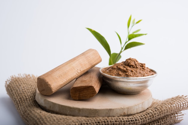 Ayurvedische Chandan of sandelhoutpasta in zilveren kom met stokken en bladeren geplaatst over sahanor sahana of ronde stenen basis voor het maken van pasta