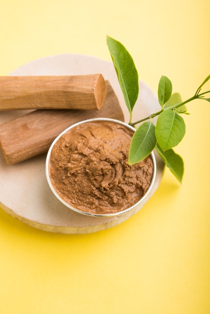 Ayurvedische Chandan of sandelhoutpasta in zilveren kom met stokken en bladeren geplaatst over sahanor sahana of ronde stenen basis voor het maken van pasta