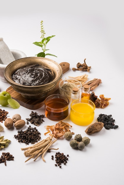 Ayurvedische Chyawanprash is een krachtige immuniteitsbooster OF een natuurlijk gezondheidssupplement. Geserveerd in een antieke kom met ingrediënten, over humeurige achtergrond, selectieve focus