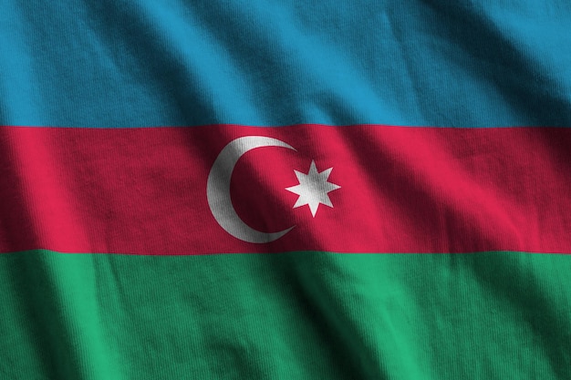 큰 주름이 있는 아제르바이잔 국기가 실내 스튜디오 조명 아래에서 가까이 흔들리고 있습니다. 배너의 공식 기호 및 색상