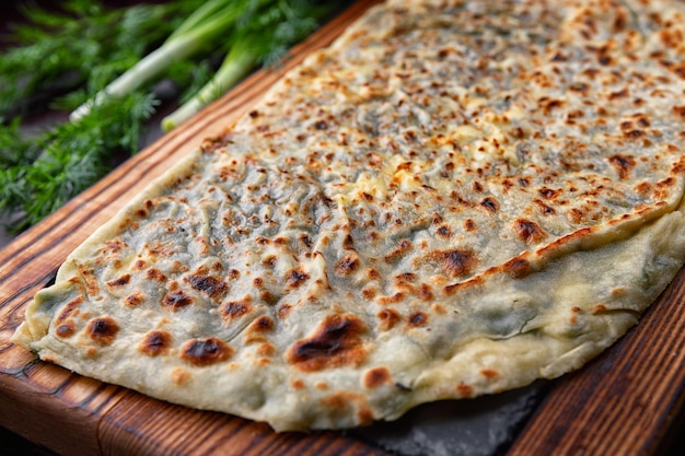 Azerbaijani kutab with herbs on a wooden board closeup selective focus