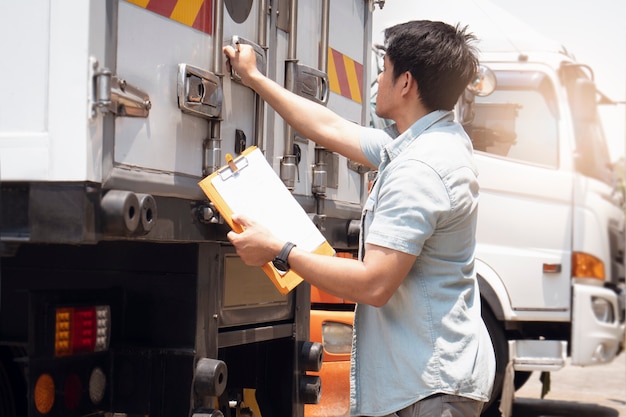 Aziaat controleert een de holdingsklembord van de vrachtwagenchauffeur het stalen deur van de veiligheidscontainer van containervrachtwagen. Vrachtvracht, logistiek en transport.