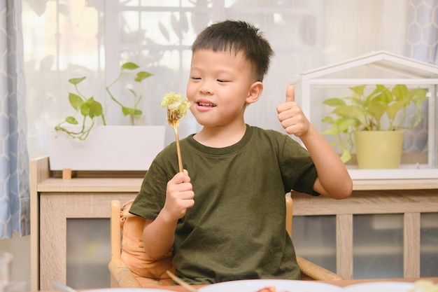 Aziatisch 5 jaar oud kleuterschooljongenskind dat salade eet Kind geniet van vegetarisch eten Gezond eten gezond levensstijlconcept Zachte en selectieve focus