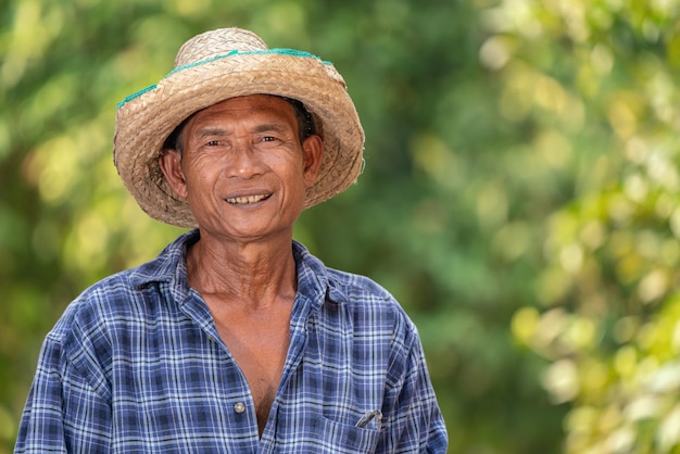 Aziatisch de plaidoverhemd van de landbouwersslijtage gelukkig in de tuin