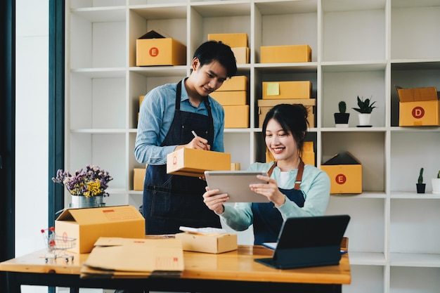 Aziatisch echtpaar doet samen online zaken thuis Helpen bij het verpakken van producten in kartonnen dozen familieconcept moderne zakelijke kleine ondernemers online levering