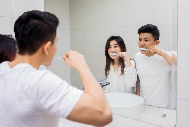 Aziatisch echtpaar poetst tanden in de badkamer.