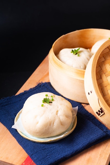 Aziatisch eten concept Chinees vlees knoedel Baozi in dim sum bamboe stoomboot op houten bord op zwarte leisteen stenen achtergrond met kopie ruimte