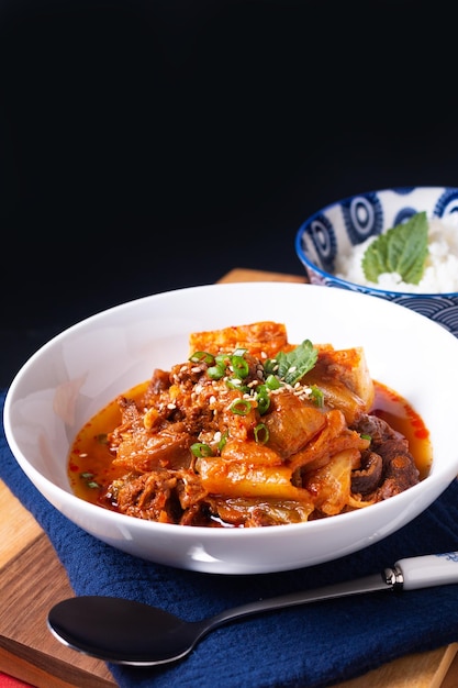 Aziatisch eten concept zelfgemaakte Kimchi Beef Stew Kimchi Jjigae op houten plank en zwarte leisteen met kopieerruimte