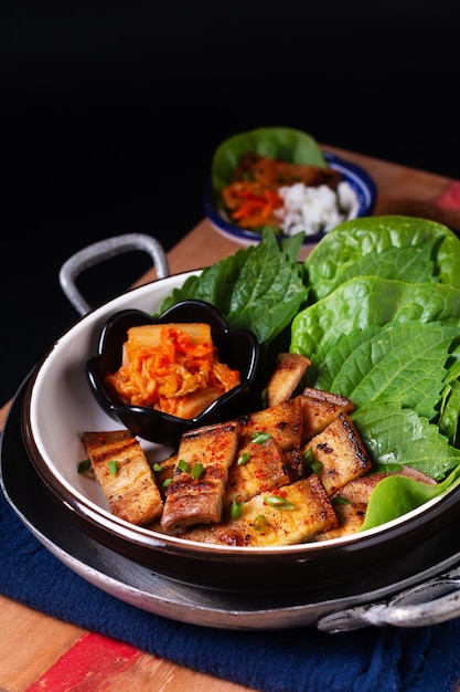 Aziatisch eten concept zelfgemaakte Koreaanse gegrilde varkensbuik Bbq Samgyeopsalgui met kimchi en shiso en salade op zwarte achtergrond met kopie ruimte