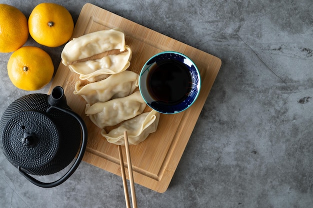 Aziatisch eten Dim sum met sojasaus op bamboe bord versierd met sinaasappels en theepot Kopieer ruimte