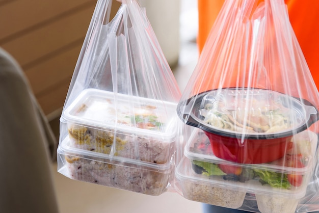 Aziatisch eten dozen in plastic zakken geleverd aan de klant thuis door bezorger