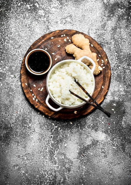 Aziatisch eten. Gekookte rijst met sojasaus op het oude bord. Op rustieke achtergrond. Japanse keukentafel.