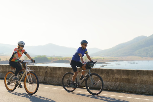 Aziatisch fietspaar rijdt samen voor lichaamsbeweging rond het meer in de ochtend
