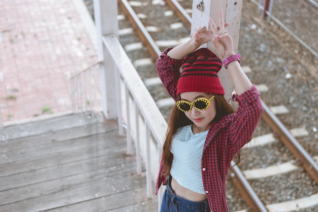 Aziatisch hipstermeisje draagt een zonnebril die poseert voor het nemen van een foto op de houten traplevensstijl van moderne vrouwThaise mensen in hippiestijl