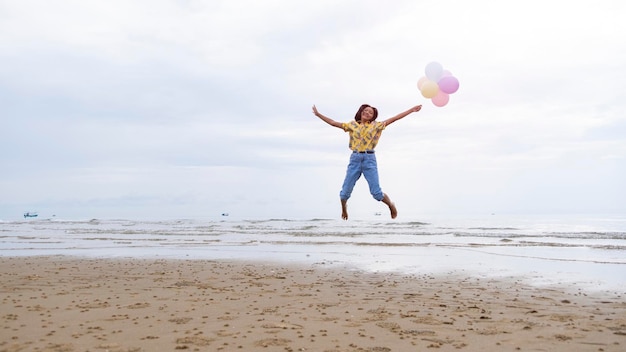 Aziatisch jong meisje geniet van het spelen van ballon op het strand