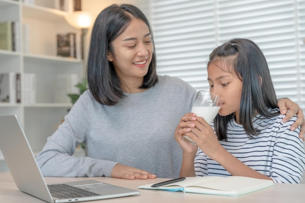 Aziatisch jong meisje leert thuis Huiswerk maken met een vriendelijke moeder die helpt bij het examen