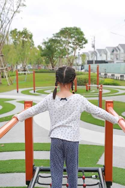 Aziatisch jong meisje spelen op apparatuur op een speelplaats Achteraanzicht