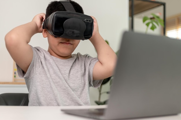 Aziatisch jongetje met VR-bril die thuis wetenschappen studeert Nieuwsgierige student draagt een virtual reality-headset om wetenschap thuis online te studeren, futuristische levensstijl te leren