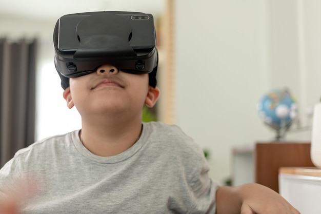 Aziatisch jongetje met VR-bril die thuis wetenschappen studeert Nieuwsgierige student draagt een virtual reality-headset om wetenschap thuis online te studeren, futuristische levensstijl te leren