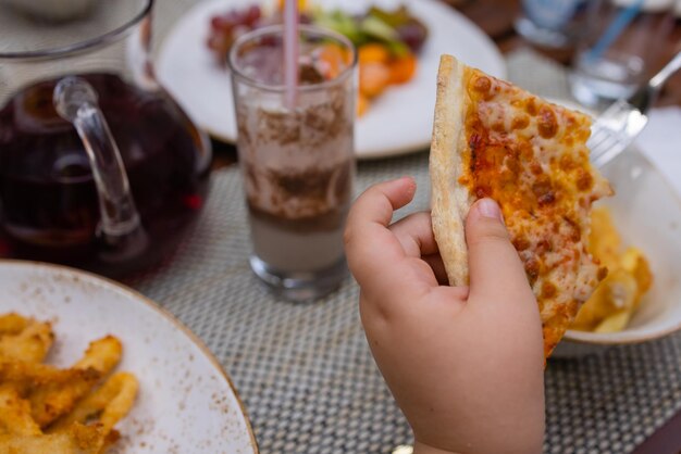 Aziatisch kind met een plakje heerlijke hete pizza boven tafel