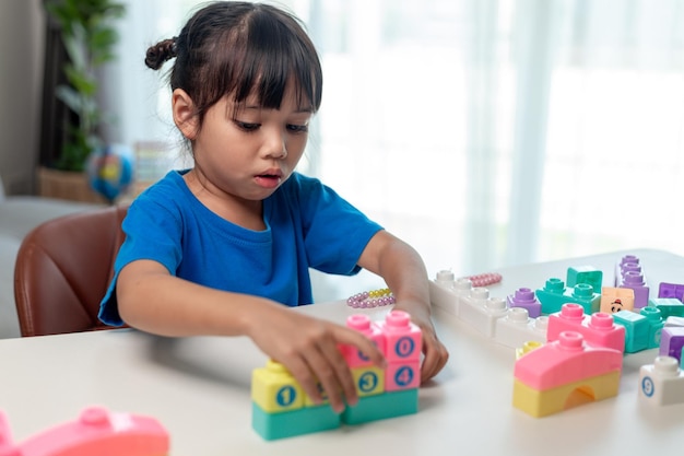 Aziatisch kindmeisje dat creatieve stuk speelgoed blokken speelt voor thuisonderwijs