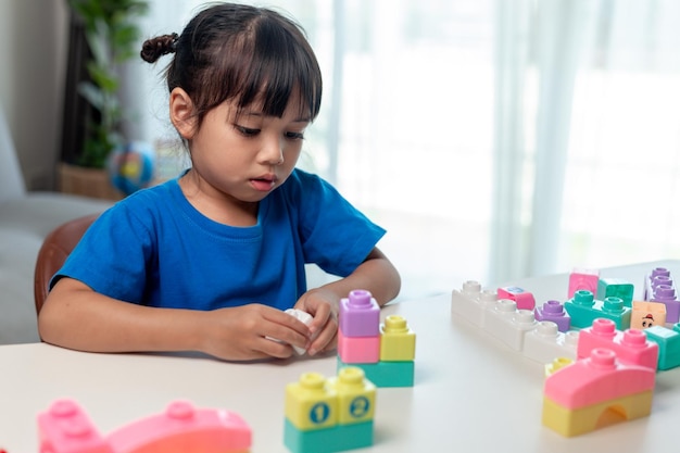 Aziatisch kindmeisje dat creatieve stuk speelgoed blokken speelt voor thuisonderwijs