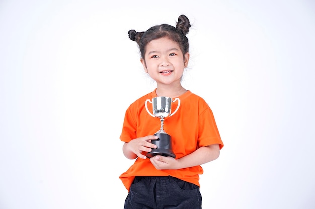 Aziatisch klein Chinees meisje glimlacht met een trofee in haar handen geïsoleerd op een witte achtergrond