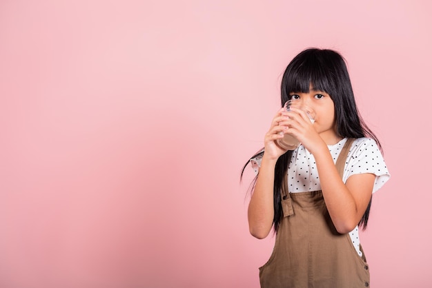 Aziatisch klein kind van 10 jaar oud lacht melkglas vast, drink witte melk en drink