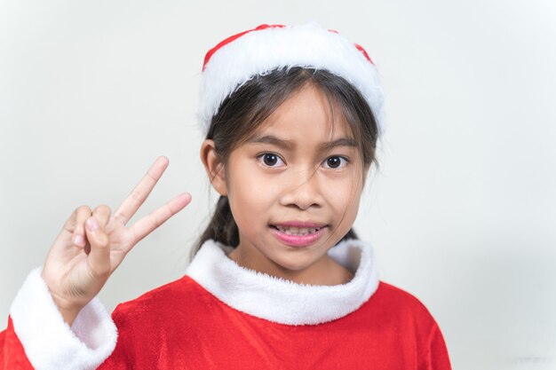 Aziatisch klein kinderenmeisje dat een rood kerstmanpak draagt om kerstvakantie thuis te vieren. Kerstvakantie Concept Stock Photo