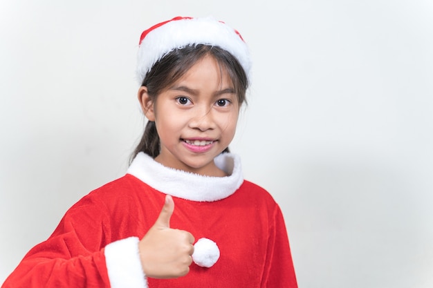 Foto aziatisch klein kindermeisje dat een rood kerstmanpak draagt om kerstvakantie thuis te vieren