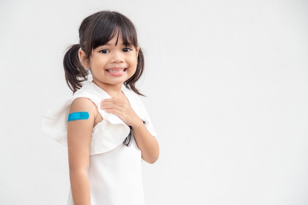 Aziatisch klein meisje dat zijn arm laat zien na vaccinatie of vaccinatie van kinderen