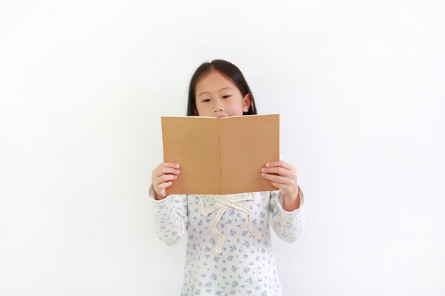 Aziatisch meisje dat bruin boek houdt en over witte achtergrond leest.