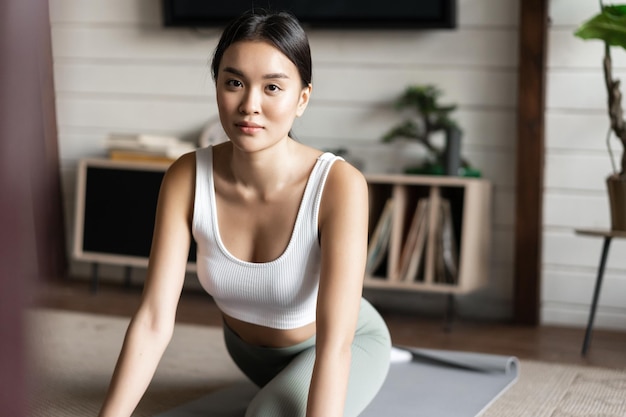 Aziatisch meisje doet yoga die zich uitstrekt thuis training in haar woonkamer met activewear