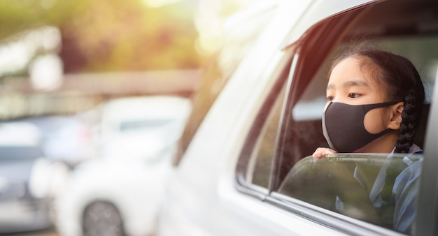 Aziatisch meisje draagt masker om stof en luchtvervuiling PM 2,5 in de auto te beschermen