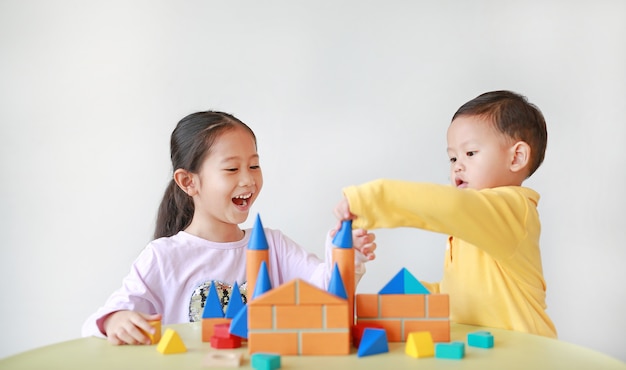 Aziatisch meisje en babyjongen spelen met houten speelgoed