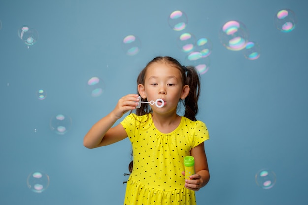 Aziatisch meisje Letn zeepbellen in de Studio op een blauw