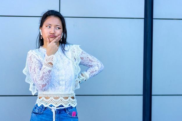 Aziatisch meisje luistert naar muziek met een koptelefoon en een twijfelende blik op haar gezicht