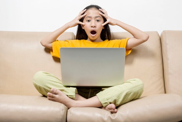 Aziatisch meisje met een laptop geschokt op online schoolklas thuis. Online onderwijs tijdens quarantaine