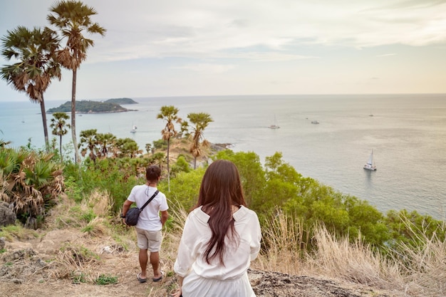 Aziatisch meisje met lang haar zit met haar achterkant voor Laem Phrom Thep of Phrom Thep Cape, de beroemde kaap op het eiland Phuket in Twilight-tijd