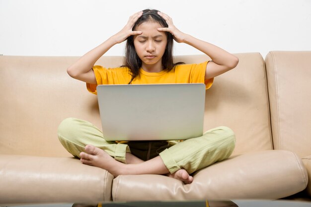 Aziatisch meisje met laptop die stress voelt voor online schoolklas thuis. Online onderwijs tijdens quarantaine