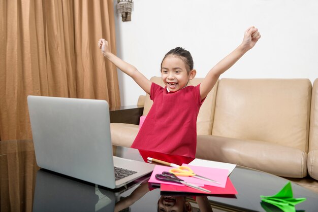 Aziatisch meisje met laptop die thuis online schoolklas bijwoont. Online onderwijs tijdens quarantaine