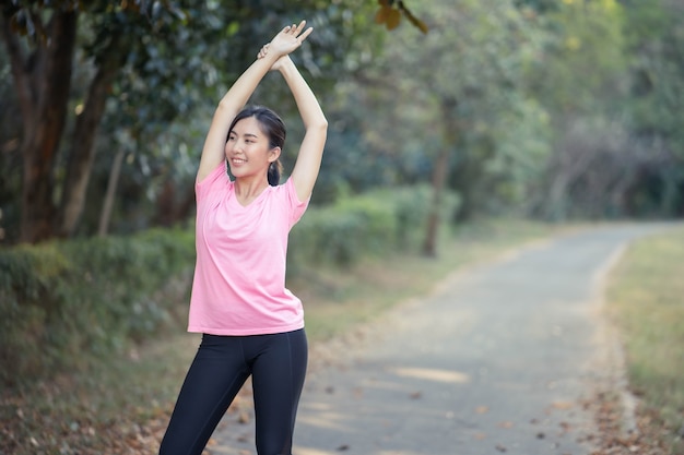 Aziatisch meisje rekt de warme spieren van haar lichaam uit voordat ze gaat hardlopen in het park